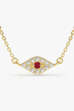 A delicate gold chain necklace featuring a horizontal, eye-shaped pendant paved with clear, sparkling stones and a single round, red gemstone in the center.