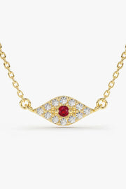 A delicate gold chain necklace featuring a horizontal, eye-shaped pendant paved with clear, sparkling stones and a single round, red gemstone in the center.