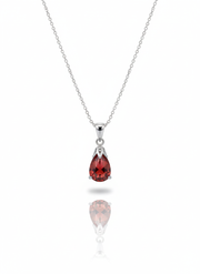 A sterling silver necklace with a key-shaped pendant on a soft neutral background. The head of the key features a cutout four-leaf clover design, and the piece has a high-polish finish.