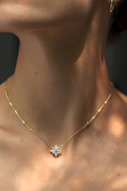 A delicate silver chain necklace with a beautifully crafted camelia flower pendant with a small pearl at the center.